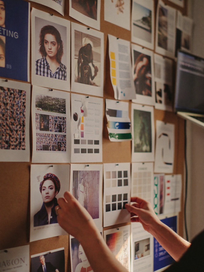 A creative mood board wall of pinned content in a warm studio.